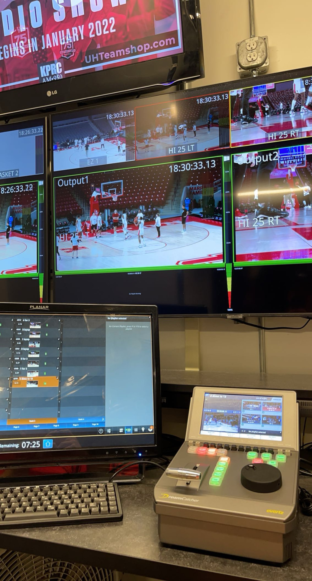 Broadcast monitors showing multiple basketball camera feeds beside a replay controller