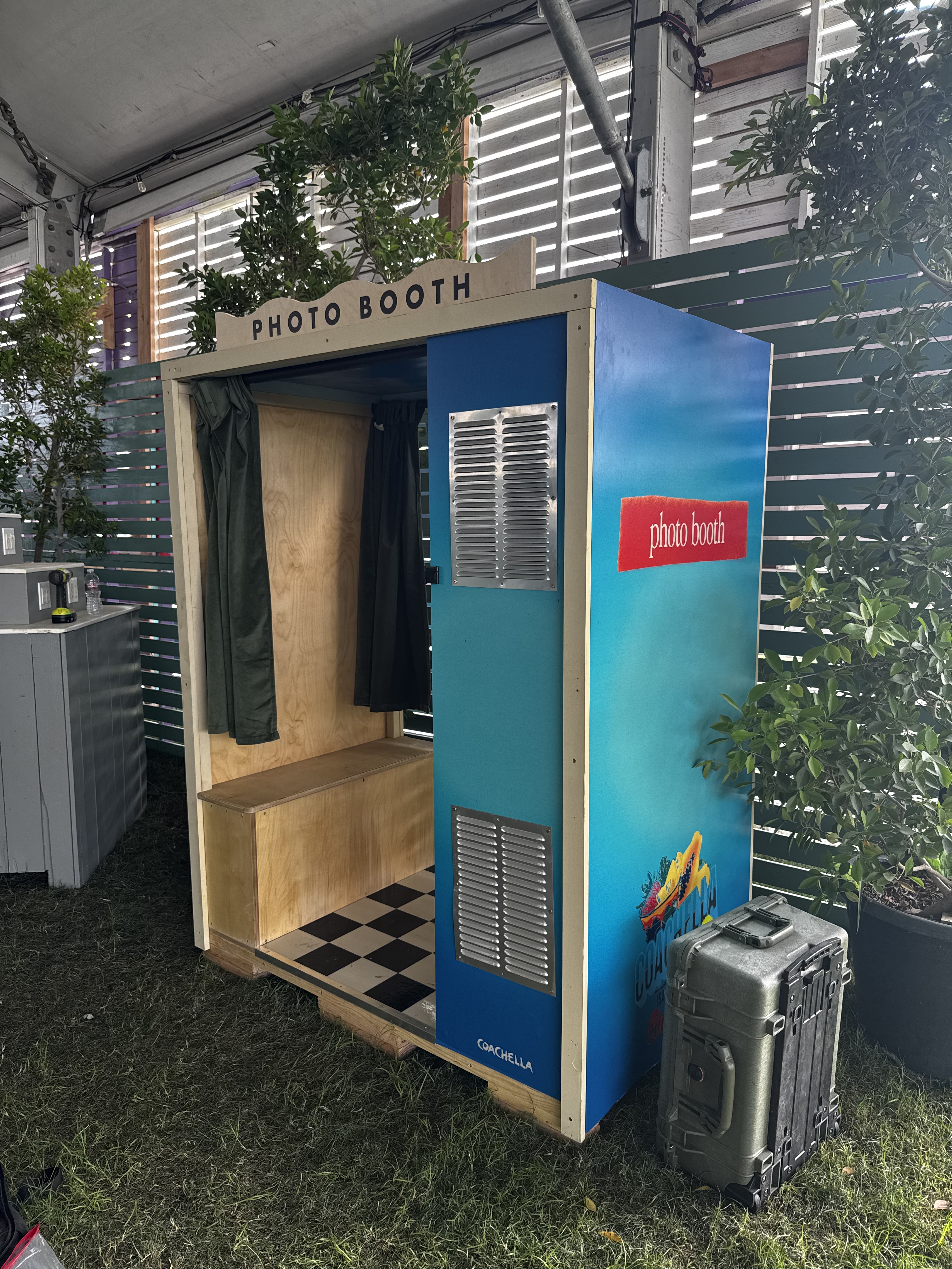 Finished blue Coachella photo booth with curtains and a checkerboard floor