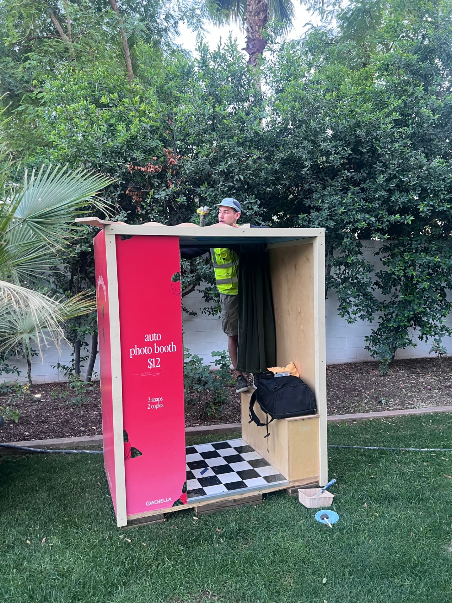 Red auto photo booth being assembled outdoors among palm trees