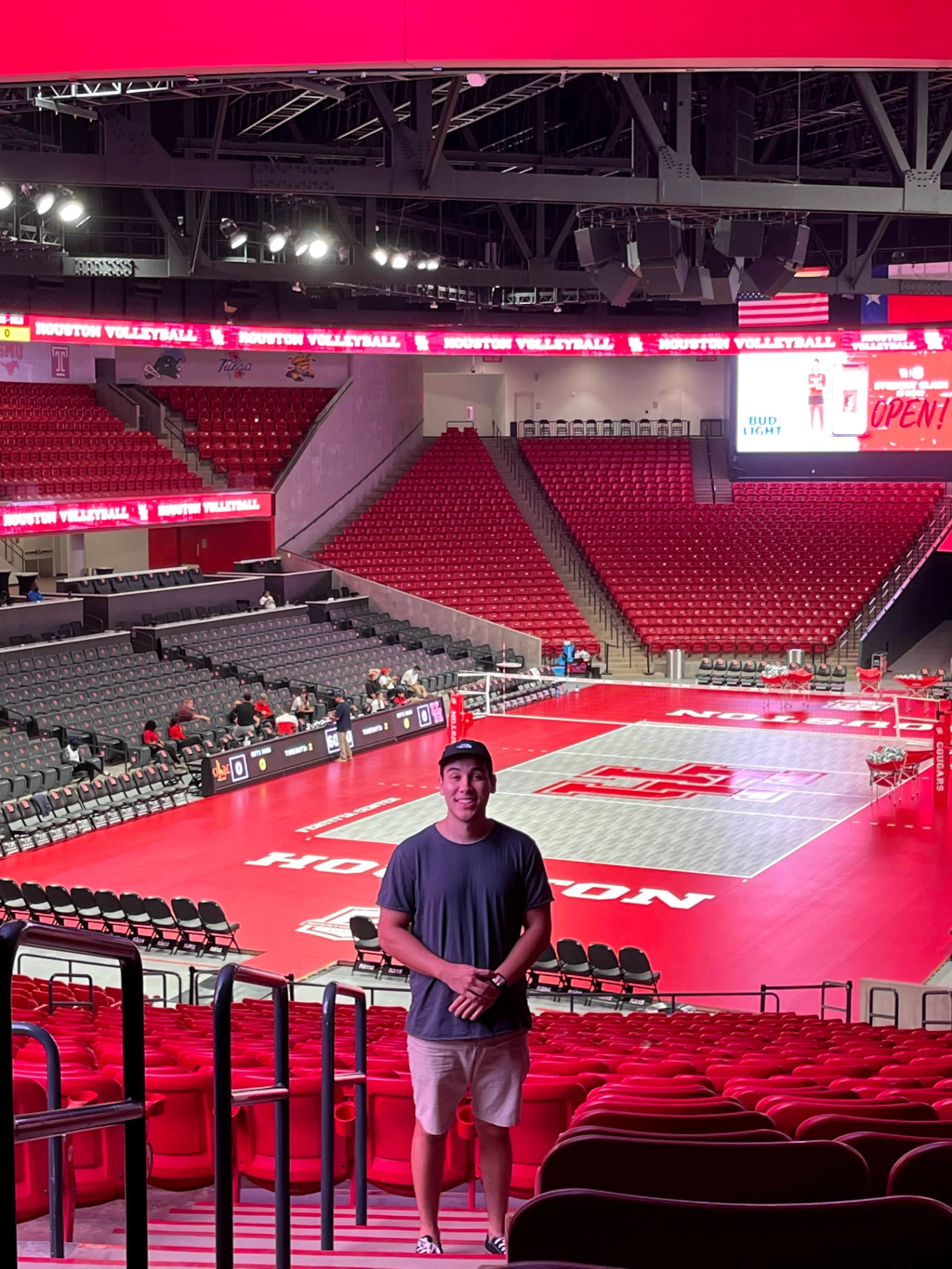 Tanner standing in the seating area above a University of Houston volleyball court before a broadcast
