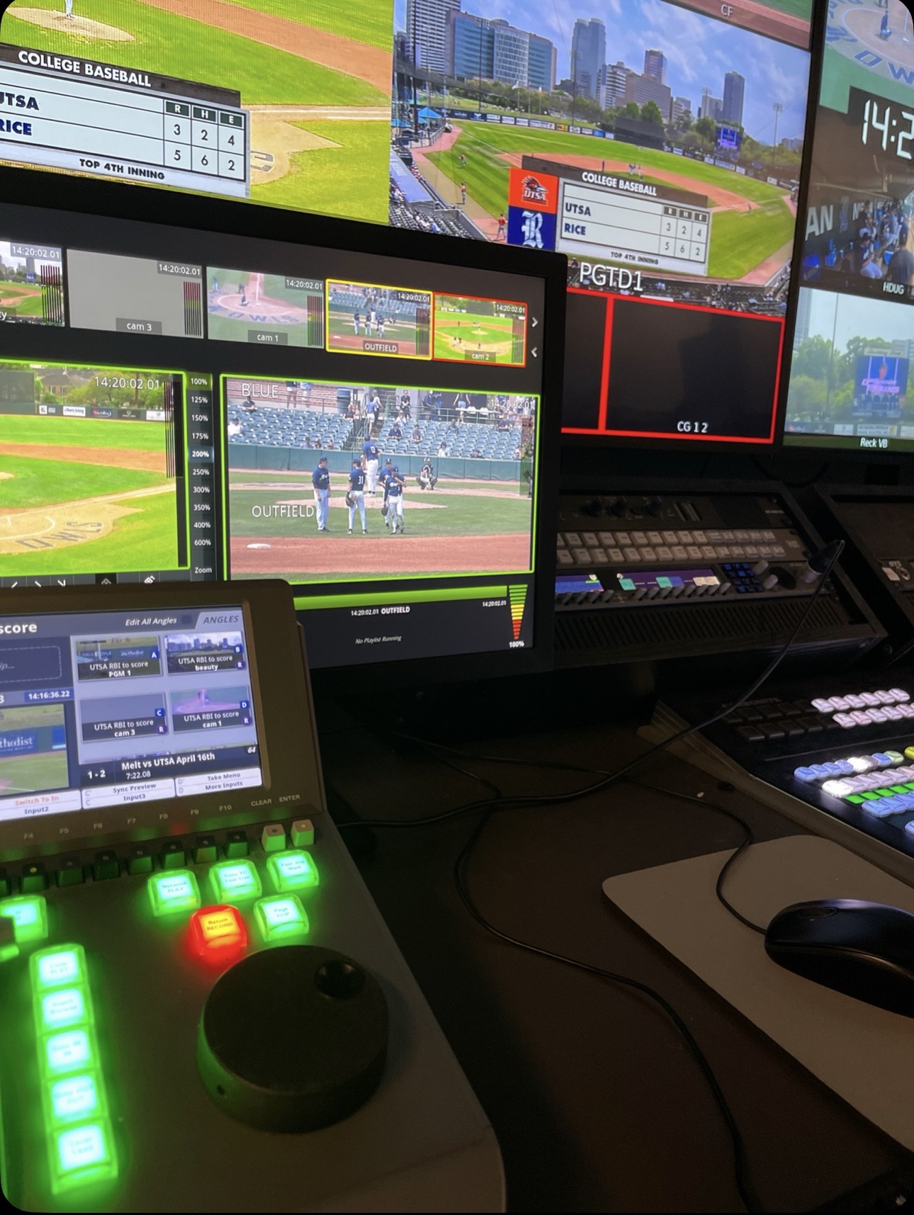 Baseball broadcast control desk with camera feeds, switchers, and illuminated controls