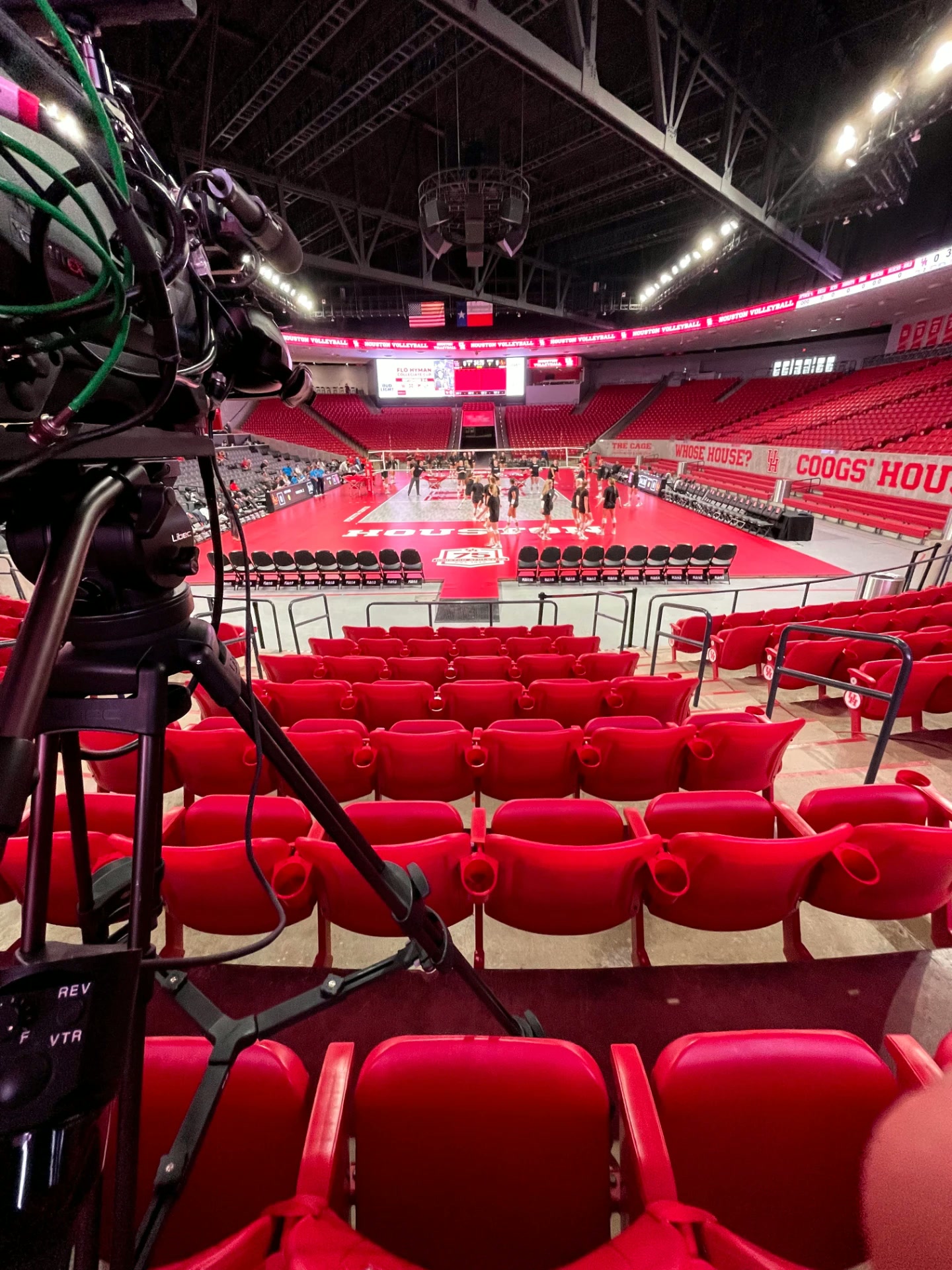 Broadcast camera overlooking a red college basketball court before a game